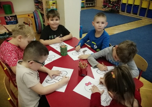 Dzieci siedzą przy stoliku i kolorują obrazek z postaci z opowiadania